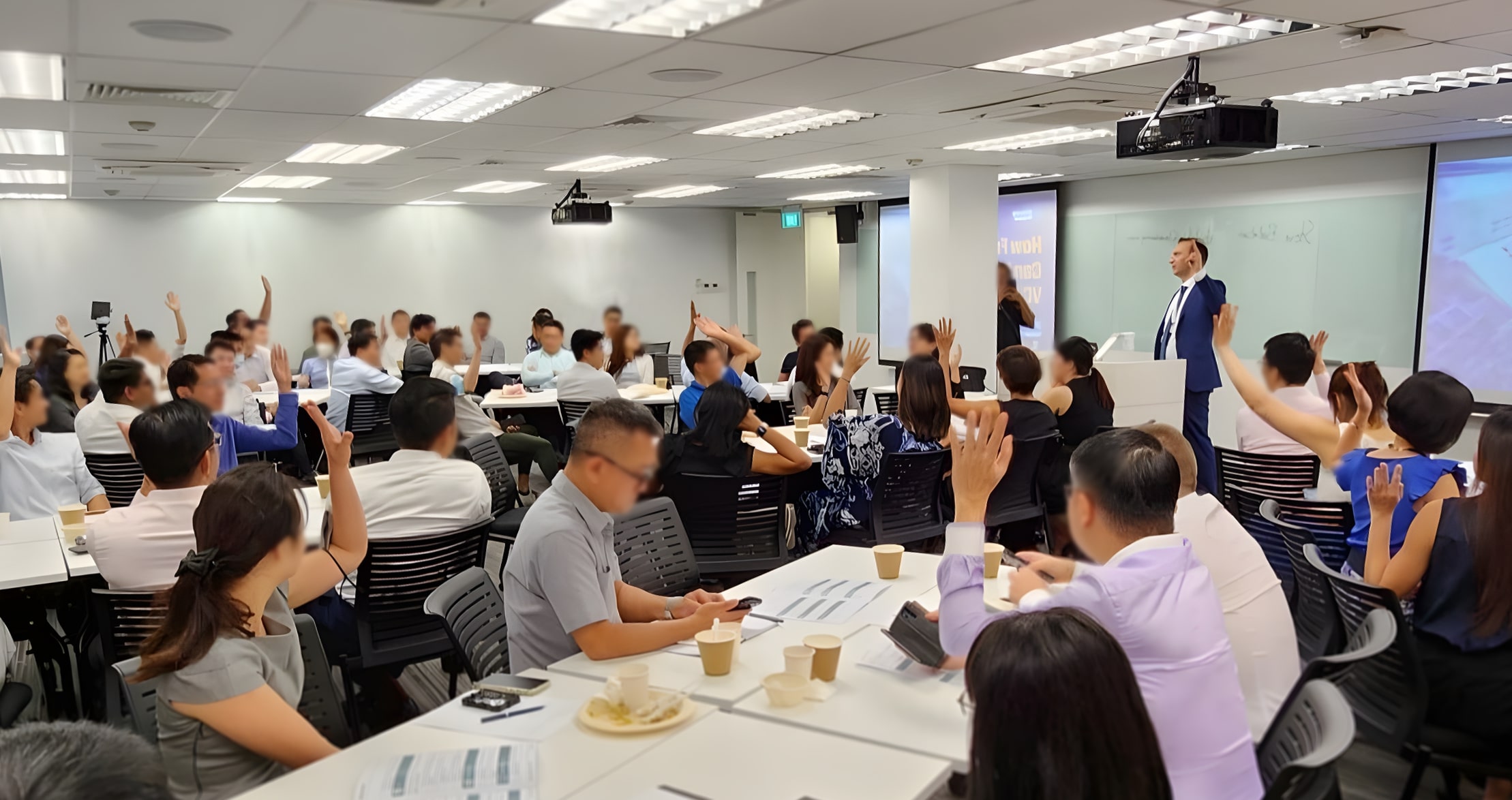 Steve Balaban speaking at an event as all listeners raise their hands.